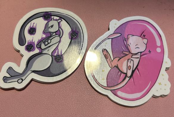 A photo of two Pokemon stickers, featuring Mew and Mewtwo.