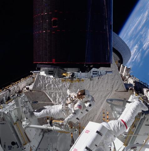 The recovered Palapa B2 satellite being held by Dale Gardner before being placed into its cradle inside the payload bay during STS-51A.