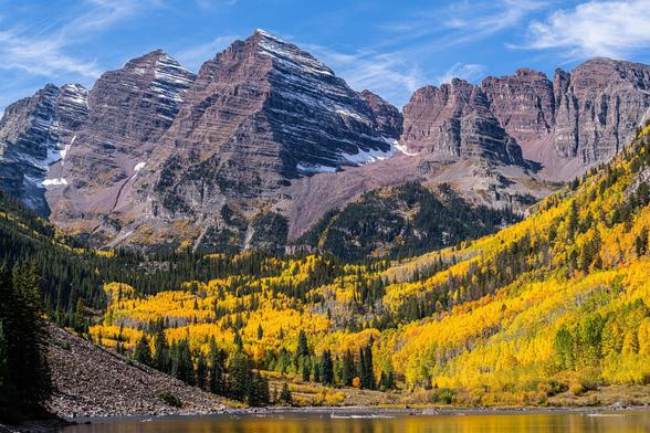 The Maroon Bells mountain peaks with yellow aspens and lake in the foreground