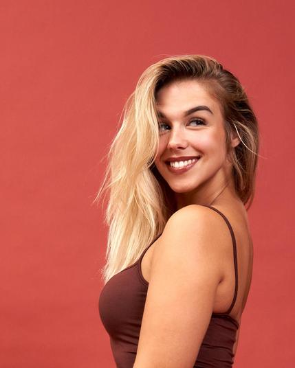 Photograph of a woman smiling radiantly, and looking to the right.