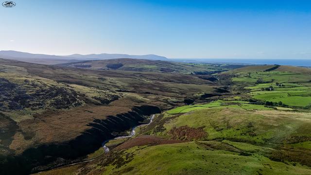 Aerial view over moorland and hills with small winding river