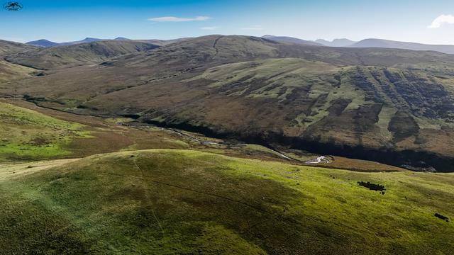 Aerial view over moorland and hills with small winding river