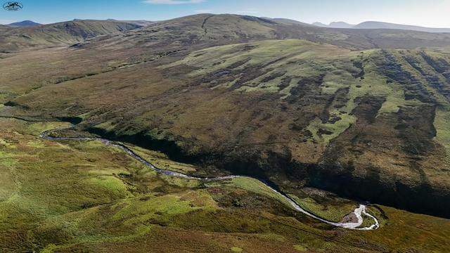 Aerial view over moorland and hills with small winding river