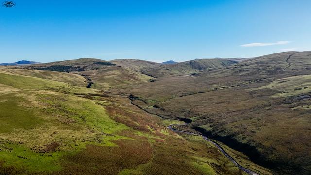 Aerial view over moorland and hills with small winding river