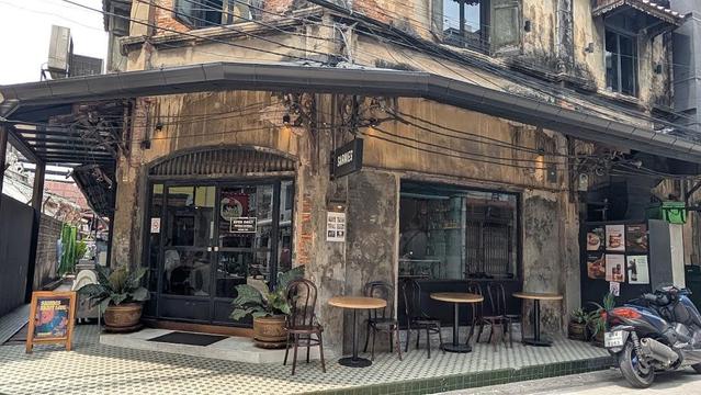 An aged building with a cafe called "Sarnies." Outdoor seating and a parked motorcycle are visible.