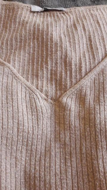 The neckline of a V-neck knit dress, which has been darned at the point of the V.