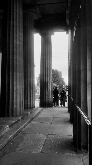 Looking along between rows of tall, Doric pillars on the front of the Neo-classical Royal Scottish Academy