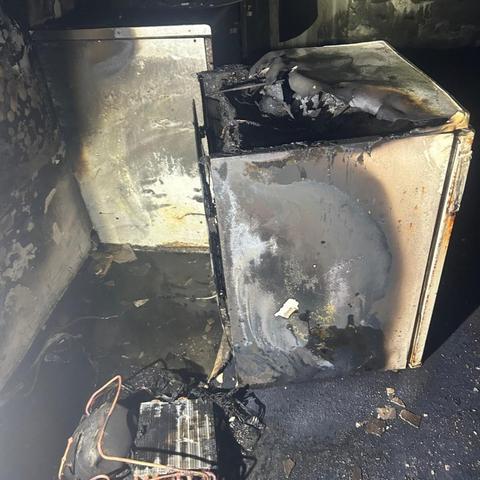 Basement room in Neath showing extensive fire damage after a dehumidifier blaze, with walls and ceiling blackened by smoke.
