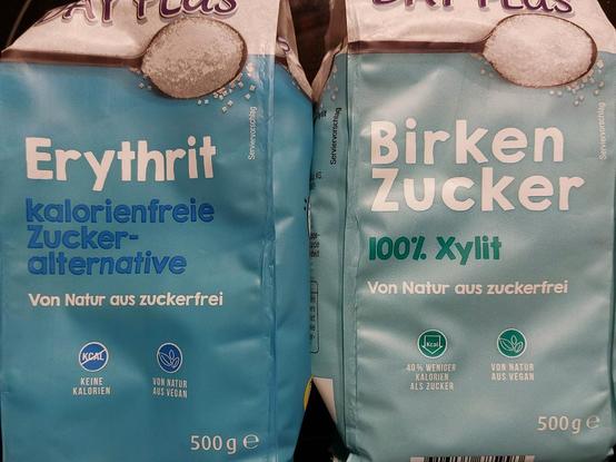 Zwei Verpackungen.
Eine mit der Aufschrift "Erythrit - kalorienfreie Zuckeralternative", die andere mit "Birken Zucker - 100%. Xylit", beide "Von Natur aus zuckerfrei".