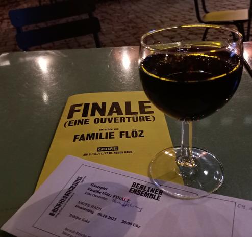 Auf dem Tisch das Programmheft, das tickt und ein glas Rotwein