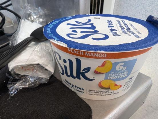 A container of Silk brand non dairy mango peach yogurt.
