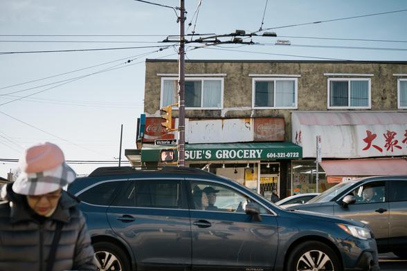 A woman crosses a busy street as traffic swarms around her.