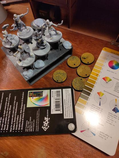 The finished bases and started miniatures next to color cards opened at "golden yellow"