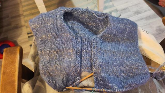 A blue upper half of a knitted cardigan with a lace border where the button band will be.