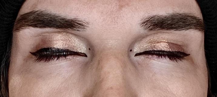 Dune's eyes up close, they're closed. they're a shimmer reddish gold with perfect black eyeliner forming wings on both sides of the eye. she also adds a small dot on the inside, giving her an insectoid false eye impression