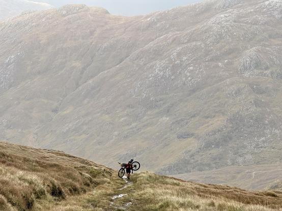 Cyclist creating a hill with bike on back.