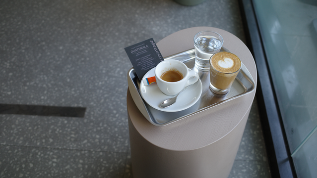 A tray with coffee, a glass of water, and a menu on a round table.