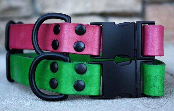 Two leather collars stacked. Top is pink, bottom is green, and both have black hardware including a side-release buckle, D-ring, and slider