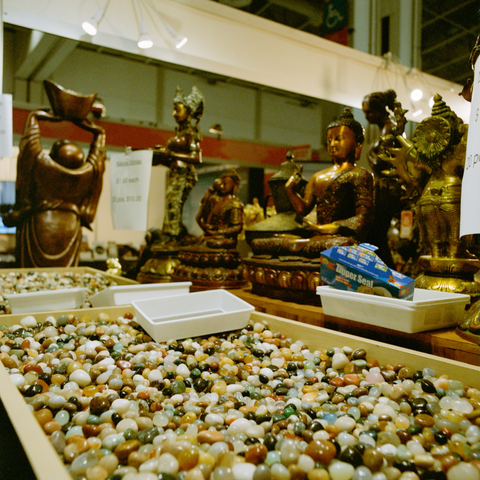 Trays of small polished stones, sold by the bag, surrounded by Buddha figures.