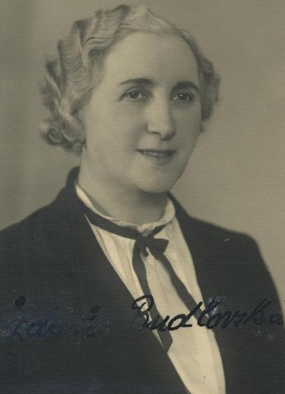 Vintage black and white portrait of a woman smiling and wearing a dark blazer with a light-colored blouse and a bow tie.