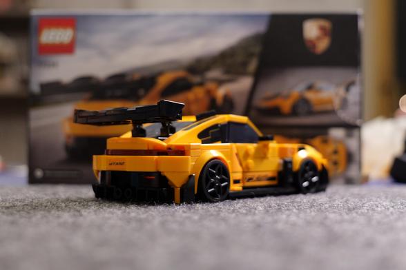 A yellow Lego Porsche 911GT3 RS in front of its own box.
