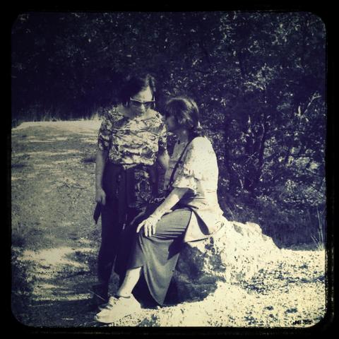 Retro-Monochromfoto, das in Bildmitte zwei Frauen im Gespräch zeigt. Die Frau rechts sitzt auf einem Felsen, die Frau links steht und hört sichtbar zu. Hintergrund ist ein Naturpark mit Gestein, Sand und Gebüsch. Leica IIIc mit 50 mm Summitar auf Rollei Retro 80-Film, editiert und beschnitten.