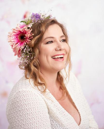 Photograph of a happy smiling woman with flowers in her hair.