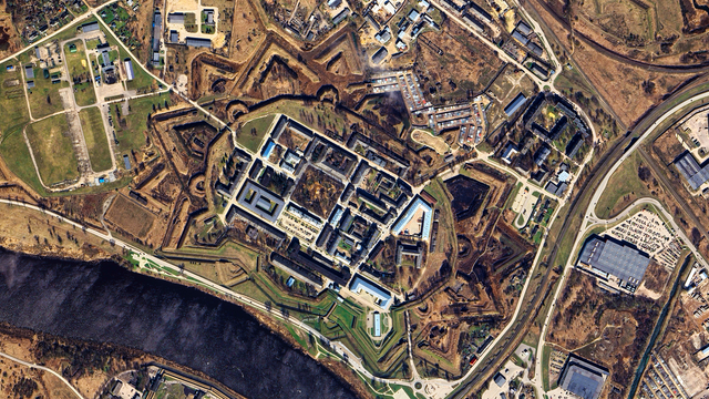A satellite picture of a large, star-shaped fortress surrounded by a moat, with multiple buildings inside and a river running nearby.
