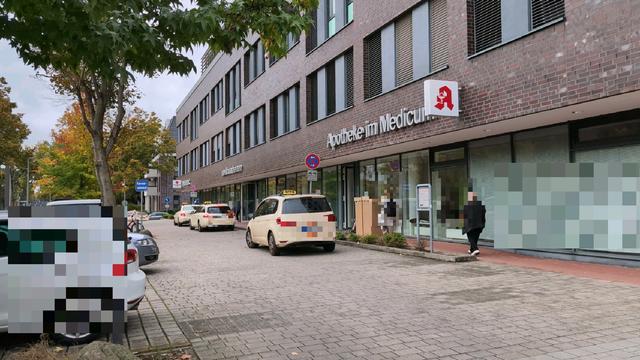 Drei Taxen stehen im als Feuerwehrstellflävhe ausgeschilderten absoluten Haltverbot vor einem Ärztehaus. Auf dem schmalen Gehweg stehen Umzugskartons.