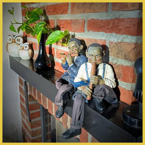 Two small nice colorful statues of flute players from a jazz orchestra on a mantelpiece.
