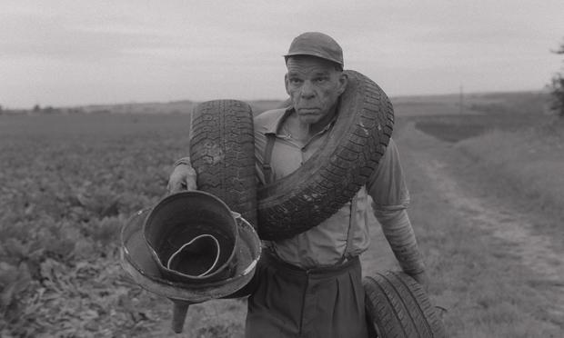 b&w shot of Denis Lavant as a man carrying scrap across a field in Redoubt