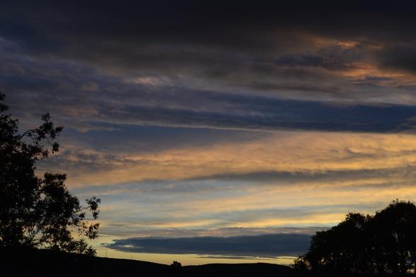 A photo of a sunset through norwester clouds over the Southern Alps as seen from the Cashmere hills of Christchurch city. This view is off to the southwest where the colours on the clouds are more subtle salmon pinks and pale orange and blue greys.

My full-res photo is on Flickr at https://www.flickr.com/photos/mollivan_jon/54844913164/