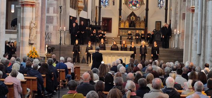 Acht schwarz gekleidete Sänger:innen im Altarraum einer vollbesetzten Kirche