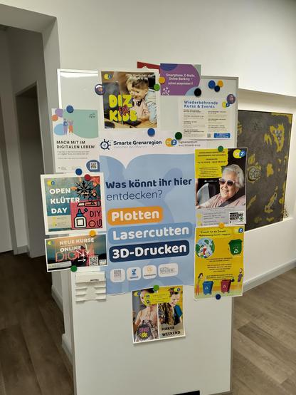 Foto von einer Wand mit verschidenen Plakaten. Auf der Mitte steht "Was könnt ihr hier entdecken
Platten
Lasercutten
3D-Drucken"