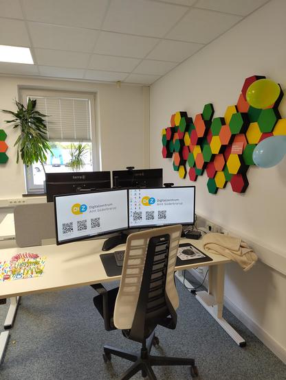 Foto von einem Arbeitplatz mit zwei Monitoren und einem Bürostuhl