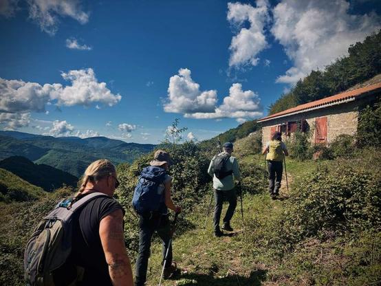 A group of hikers four heading towards a refuge, with a scenic set of hills on the horizon