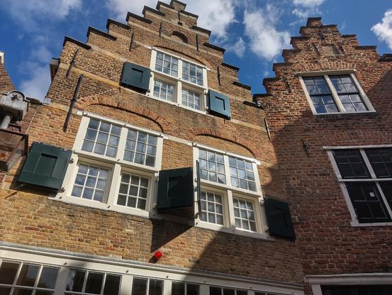 Foto van de trapgevel van een 17e eeuws bakstenen huis aan de Kuiperspoort in Middelburg. Het huis heeft drie ramen op twee verdiepingen. | Photo of the stepped gable of a 17th-century brick house on Kuiperspoort in Middelburg. The house om has three windows on two floors.