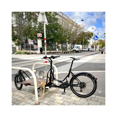 Das Radkutsche Rapid Lastenrad an einem Fahrradbügel an einer schmalen Straße mit Schienen