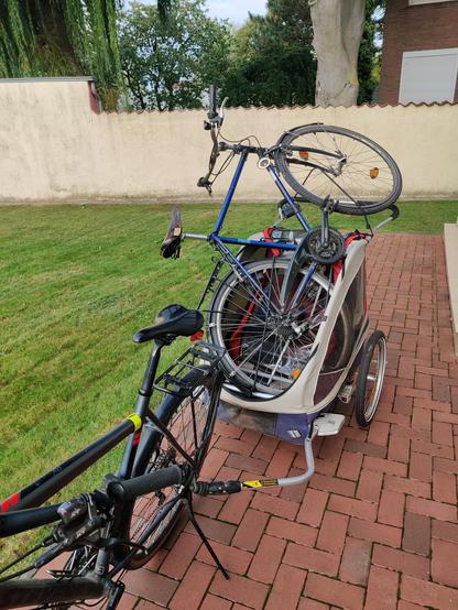 Ein Fahrrad mit einem Anhänger auf den ein anderes Fahrrad geschnallt ist.