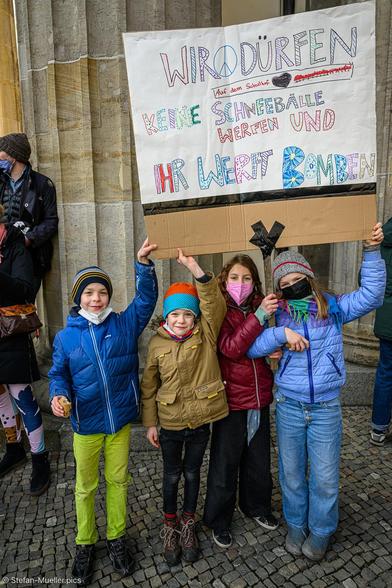 Kinder protestieren gegen den Krieg in der Ukraine. Auf dem Schild steht: „Wir dürfen auf dem Schulhof keine Schneebälle werfen und Ihr werft Bomben“, Brandenburger Tor, Berlin, 27.02.22