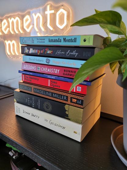 A photo of a stack of books:

Cultish by Amanda Montell
The Ministry of Time by Kaliene Bradley
Happy-Go-Lucky by David Sedaris
Lessons in Chemistry by Bonnie Garmus
Pole Dancing to Gospel Hymns by Andrea Gibson
The Memory Police by Yoko Ogawa
Circe by Madeline Miller
The City of Brass by S.A. Chakraborty
The Goldfinch by Donna Tartt