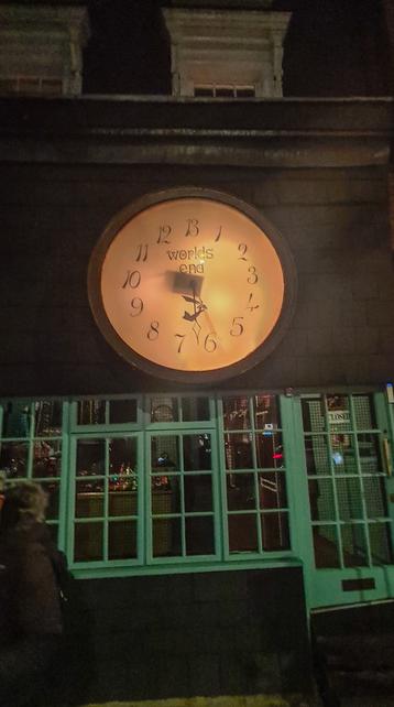 Under two small air vents someone has drawn a mouth with its tongue sticking out, and above the vents are two eyebrows, creating the appearance of a face.
A large clock above a shop window has the text "Worlds end" on it, and its one clear clock hand has the image of an arm holding a sword attached to it.