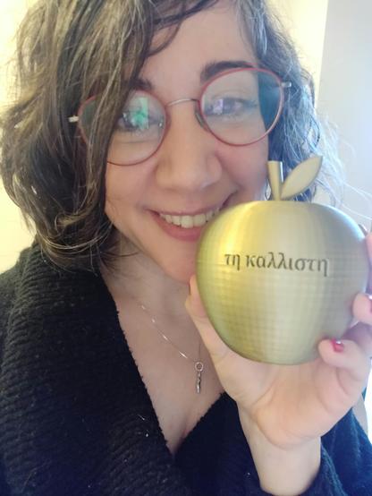 Laura muestra una manzana dorada que reza Ti kallisté