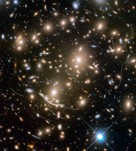 Hubble image of galaxy cluster Abell 370, showing hundreds of galaxies, curved arcs of light from gravitational lensing, and faint white streaks from nearby asteroid trails.
