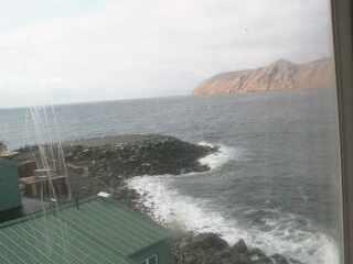 A low resolution image captured by a webcam overseeing a small peninsula with a few buildings at the front of the view.
