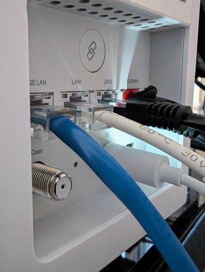 Blue, white and black Ethernet cables plugged into the ports on the back of a white Verizon Fios-branded wireless router.