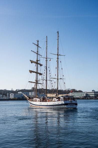 A sailing boat still without sails leaves the more with motor support on a beautiful morning
