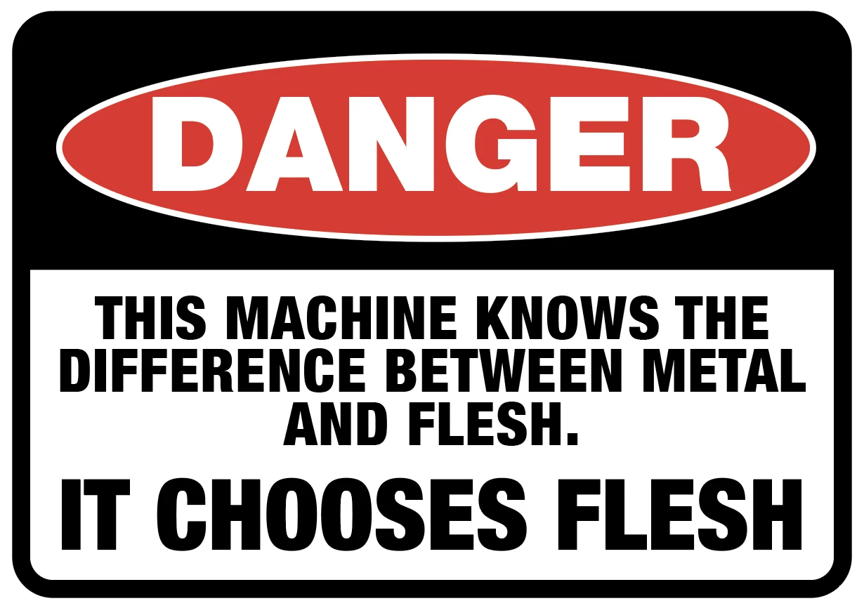 A classic DANGER warning sign. It has a red oval above against a black background with "DANGER" written inside it in thick white text. Below in bold black text on the remaining white background it states "THIS MACHINE KNOWS THE DIFFERENCE BETWEEN METAL AND FLESH. IT CHOOSES FLESH."
