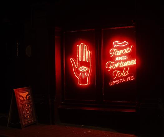 Red neon sign advertising Tarot readings upstairs.