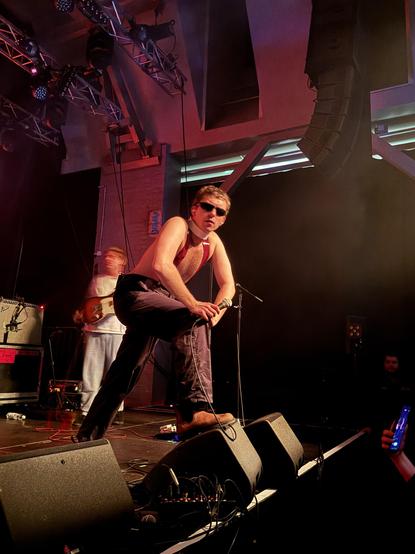 Vocalist with one leg on amp looking into camera